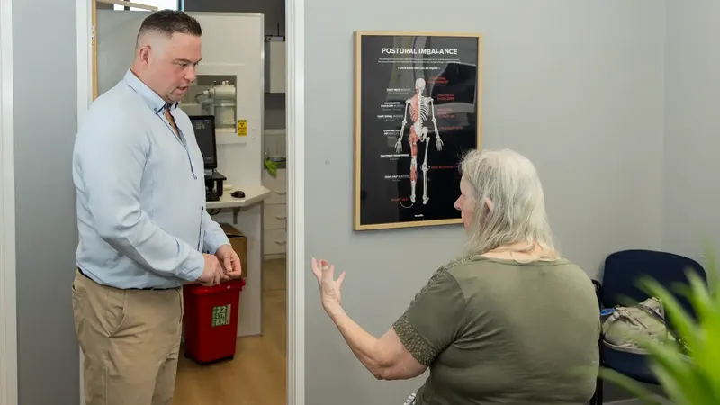Dr Michael Charlton (Chiropractor) talking with an adult in the clinic
