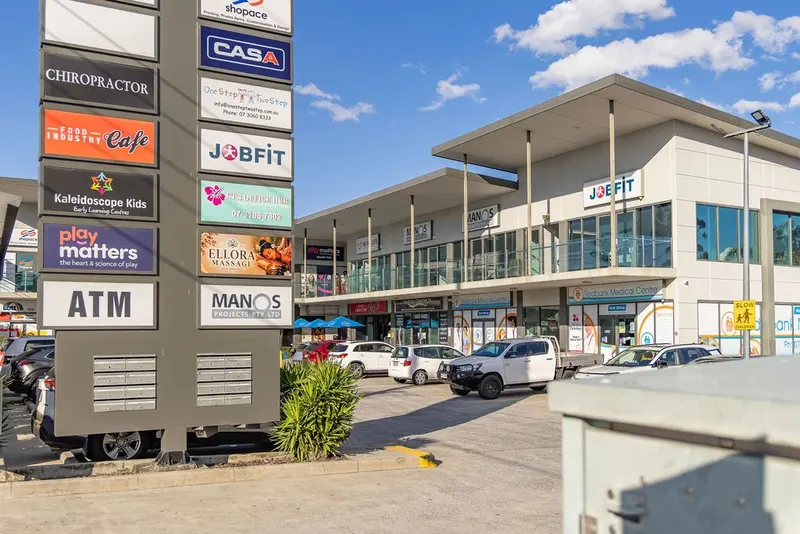 Shopping centre exterior, parking area and chiropractor pylon sign on Brisbane Road in Redbank